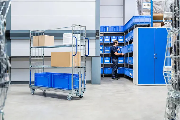 Logistics trolley carrying crates and cartons beside warehouse shelving